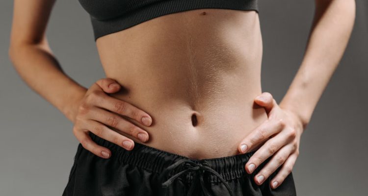 Focused shot of a woman's torso showing athletic physique in a studio setting.